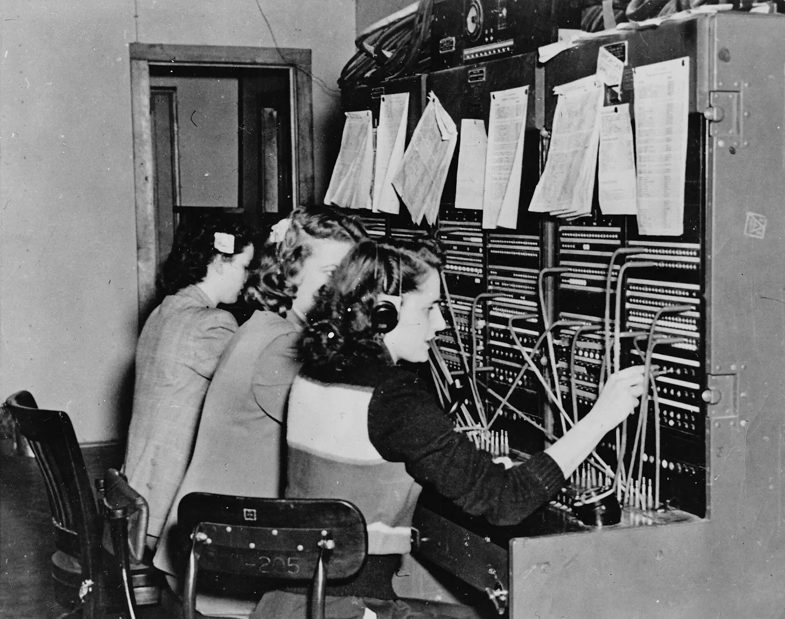Telefonistas ligando chamadas numa mesa telefônica, anos 1940